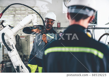 Factory workers working with adept robotic arm in a workshop Factory workers working with adept robotic arm in a workshop 88519223