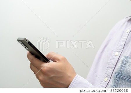 Close-up of the upper body where a man is operating a smartphone 88520018