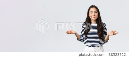 Lifestyle, beauty and fashion, people emotions concept. Clueless and unbothered asian woman shrugging with hands spread sideways and unaware smirk, standing white background 88522522