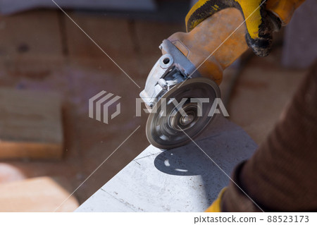 The worker cuts the tiles with a special tool with a diamond disc 88523173