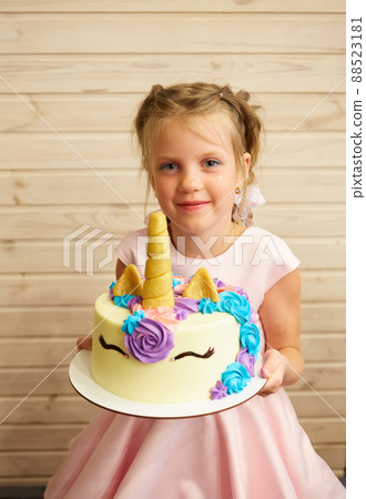 girl holding a cake in the form of a Unicorn 88523181