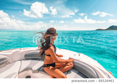 Luxury yacht woman enjoying freedom on deck in the wind relaxing on high end boat summer vacation trip upscale lifestyle of young rich people. Elegant black bikini, long hair and sun tanned body 88526461