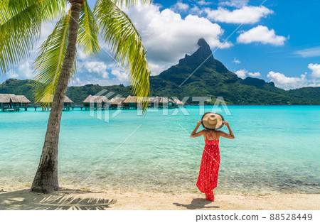 Luxury beach vacation travel destination tourist woman walking on Bora Bora island enjoying holiday in Tahiti, French Polynesia with Mount Otemanu and overwater bungalows villas hotel landscape. Luxury beach vacation travel destination tourist woman walking on Bora Bora island enjoying holiday in Tahiti, French Polynesia with Mount Otemanu and overwater bungalows villas hotel landscape. 88528449