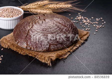 Fresh baked homemade brown bread on a black concrete background with wheat grains 88536839