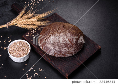Fresh baked homemade brown bread on a black concrete background with wheat grains 88536843