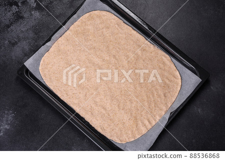 Rolled out prepared raw dough on parchment and baking sheet 88536868