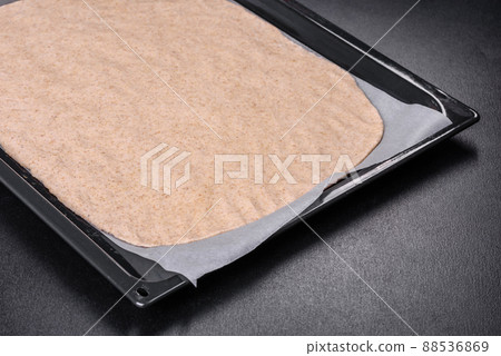 Rolled out prepared raw dough on parchment and baking sheet 88536869