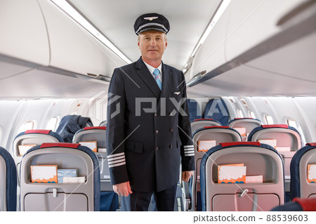 Male pilot standing in passenger airplane cabin Male pilot standing in passenger airplane cabin 88539603