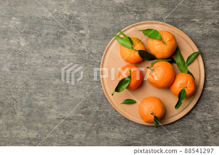 Fresh cutted clementines and whole mandarin over round plate on colored background. Food and drink ingredients preparing. healthy eating theme top view vith copy space Fresh cutted clementines and whole mandarin over round plate on colored background. Food and drink ingredients preparing. healthy eating theme top view vith copy space 88541297