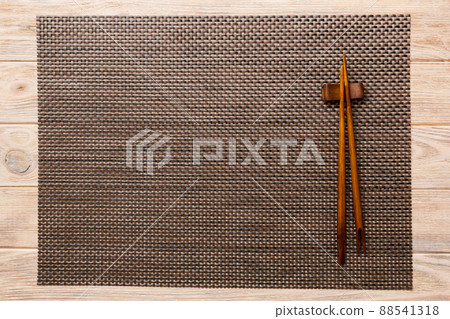 Two chopsticks and bamboo mat on wooden background. Top view, copy space 88541318