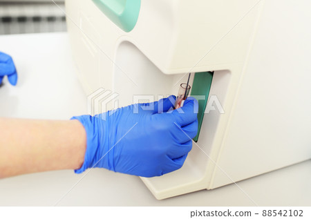 laboratory assistant examines a blood sample in an analyzer in a modern microbiological clinic. laboratory assistant examines a blood sample in an analyzer in a modern microbiological clinic. 88542102