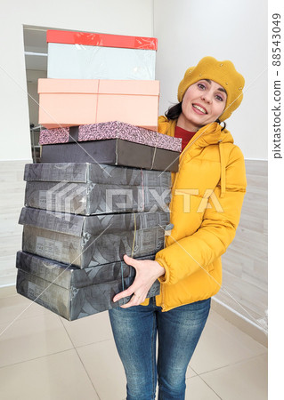 A 35-40-year-old woman with a smile holds a lot of boxes with shoes, the concept of buying an ideal buyer A 35-40-year-old woman with a smile holds a lot of boxes with shoes, the concept of buying an ideal buyer 88543049