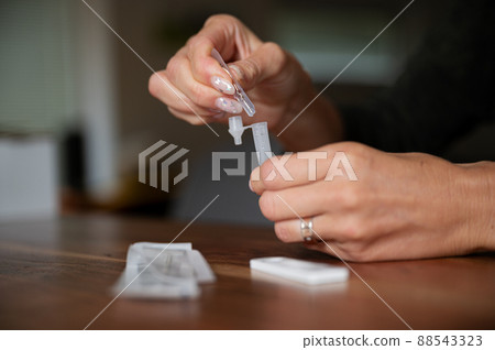 Female hands holding testing solution tube of covid19 home self test kit 88543323