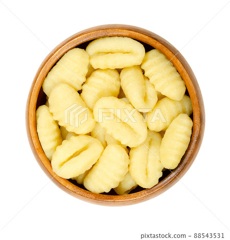 Raw gnocchi, Italian dumplings, in a wooden bowl. Made of small lumps of dough, with ridges in the size of a thumb. Composed of potato and ordinary wheat flour, ready to boil or to fry in a pan. Photo Raw gnocchi, Italian dumplings, in a wooden bowl. Made of small lumps of dough, with ridges in the size of a thumb. Composed of potato and ordinary wheat flour, ready to boil or to fry in a pan. Photo 88543531