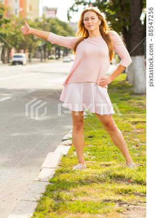 Pretty girl young woman traveler hitchhiking with thumb up hand gesture during summer vacation on mountain road 88547256