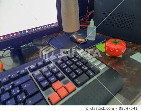 Pomodoro timer in form of a red tomato laying on a wooden table 88547541
