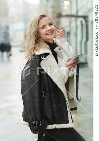 young blond slavic woman with cell phone in black leather jacket closeup street portrait young blond slavic woman with cell phone in black leather jacket closeup street portrait 88549923