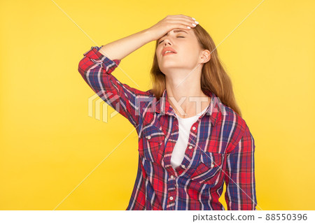 Facepalm. Portrait of regretful unhappy ginger girl in casual shirt holding hand on face, feeling desperate about loss, sorrow for mistake, bad memory. indoor studio shot isolated on yellow background 88550396
