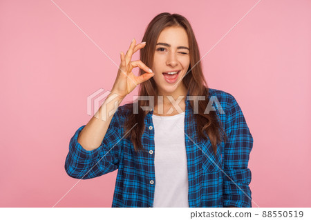 I'm ok. Portrait of cheerful optimistic girl in shirt winking at camera and gesturing okay sign, completely agree with suggestion, confident in success. indoor studio shot isolated on pink background I'm ok. Portrait of cheerful optimistic girl in shirt winking at camera and gesturing okay sign, completely agree with suggestion, confident in success. indoor studio shot isolated on pink background 88550519