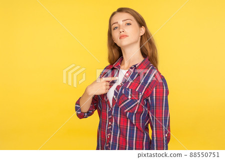 This is me. Portrait of selfish haughty ginger girl in checkered shirt pointing at herself, looking at camera with arrogance and pride, egoistic person. studio shot isolated on yellow background 88550751