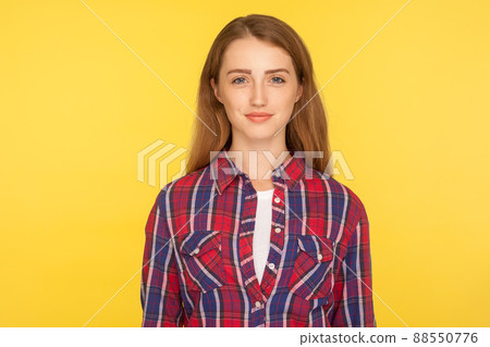 Portrait of happy attractive ginger girl in checkered shirt standing, looking at camera with positive cheerful expression, clean face skin, beauty care. studio shot isolated on yellow background 88550776