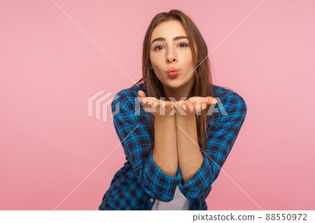 Portrait of charming girl in shirt sending sensual air kiss over palms, expressing tender romantic emotions and looking with love, flirting to camera. indoor studio shot isolated on pink background Portrait of charming girl in shirt sending sensual air kiss over palms, expressing tender romantic emotions and looking with love, flirting to camera. indoor studio shot isolated on pink background 88550972