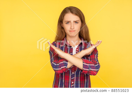 No, this is the end. Portrait of serious bossy ginger girl in checkered shirt crossing hands, gesturing warning or prohibition, meaning stop finish. indoor studio shot isolated on yellow background 88551023