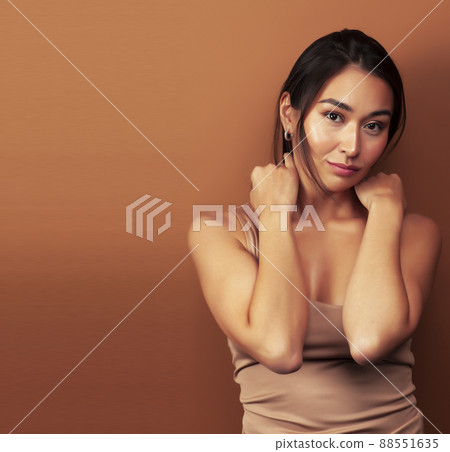 young pretty asian woman cheerful smiling posing on warm brown background, lifestyle people concept 88551635