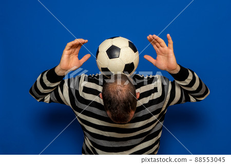 Hispanic man with incipient baldness trying to juggle a soccer ball, he has the ball on the back of his neck while raising his arms. Isolated on blue studio background Hispanic man with incipient baldness trying to juggle a soccer ball, he has the ball on the back of his neck while raising his arms. Isolated on blue studio background 88553045