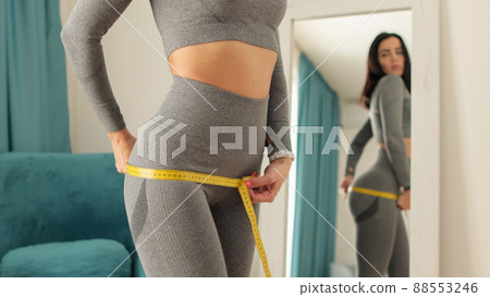 slim Woman waist Measuring With Tape at home 88553246