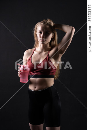 Spotrsman her shaker pink holds in hand a girl in black background shaker pink black workout, In the afternoon gym lifestyle from young and training athlete, strong wellness. Care model Spotrsman her shaker pink holds in hand a girl in black background shaker pink black workout, In the afternoon gym lifestyle from young and training athlete, strong wellness. Care model 88553575