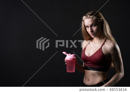 Hand holds her shaker in pink a girl spotrsman in black background shaker pink sports workout, from health lifestyle from sport from trainer athlete, sportswear people. Sweat weight empty space 88553616