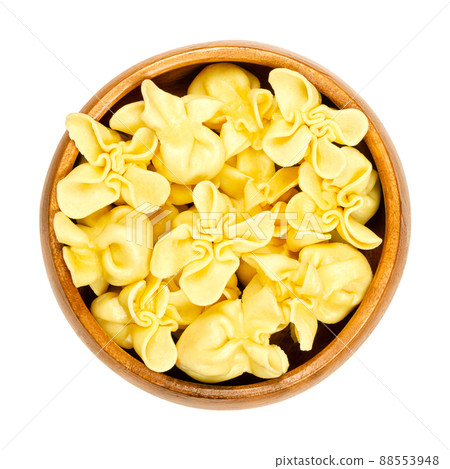 Fagottini, filled Italian pasta, dumplings in a wooden bowl. Typically shape, made by cutting pasta dough into squares, placing the filling in the center, and folding the corners to meet in a point. Fagottini, filled Italian pasta, dumplings in a wooden bowl. Typically shape, made by cutting pasta dough into squares, placing the filling in the center, and folding the corners to meet in a point. 88553948