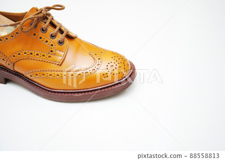 Shiny full brogue leather shoes shot against a white tile floor background Shiny full brogue leather shoes shot against a white tile floor background 88558813