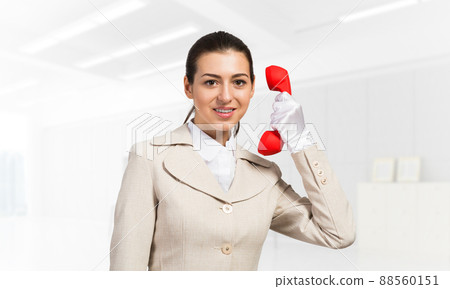 Smiling young woman holding retro red phone Smiling young woman holding retro red phone 88560151
