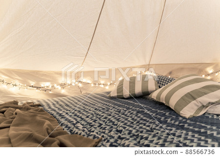 glamping tent interior detail with bed pillows and intimate lights 88566736