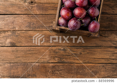 Overhead shot of tasty plums onions in crate on rustic wooden table with copyspace Overhead shot of tasty plums onions in crate on rustic wooden table with copyspace 88569996