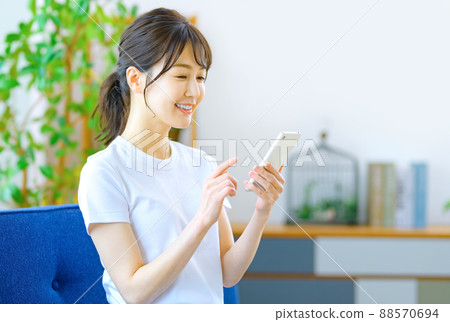 A young woman operating a smartphone in a room A young woman operating a smartphone in a room 88570694