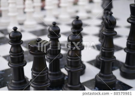 Black and white chess pieces standing on boards on street closeup Black and white chess pieces standing on boards on street closeup 88570981