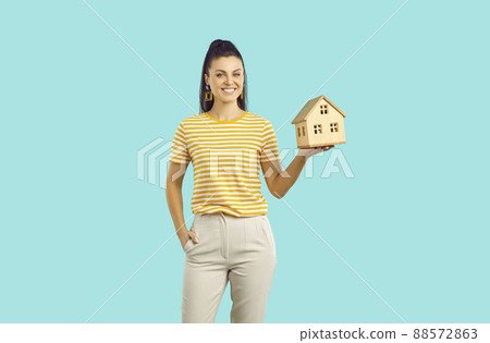 Woman on colored background holds small house as symbol of construction or loan to buy home. Woman on colored background holds small house as symbol of construction or loan to buy home. 88572863