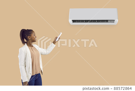 Smiling black woman turn air conditioner with remote Smiling black woman turn air conditioner with remote 88572864
