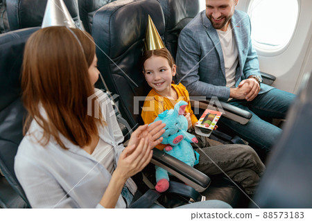 Happy parents celebrating kid birthday in airplane 88573183