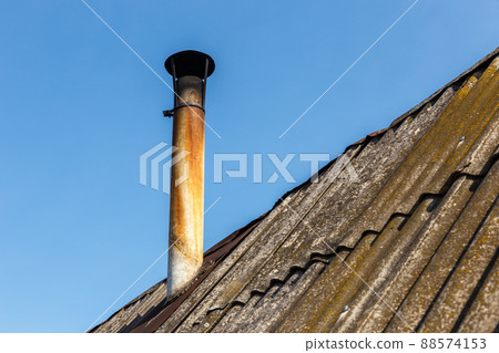 Chimney pipe on the roof of the house against the blue sky. Chimney pipe on the roof of the house against the blue sky. 88574153