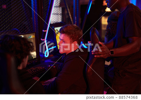 Group of young multi-ethnic men sitting in front of powerful computer and spending time in gaming club Group of young multi-ethnic men sitting in front of powerful computer and spending time in gaming club 88574368