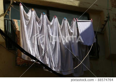 Washed clothes and linen are dried on a line outside a window in Israel 88574764