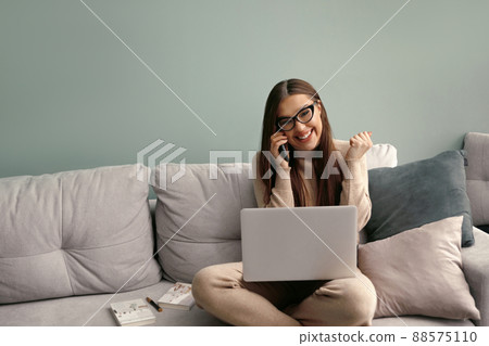 Happy Business Woman Using Laptop Computer and Talking on Mobile Phone Happy Business Woman Using Laptop Computer and Talking on Mobile Phone 88575110