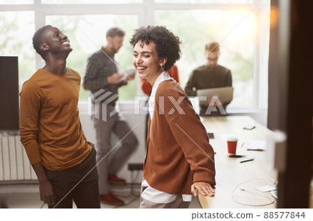 cheerful young employees standing near a table in a coworking ce 88577844
