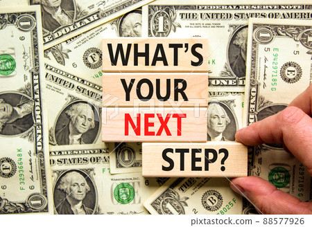 What is your next step symbol. Concept words What is your next step on wooden blocks. Businessman hand. Beautiful background from dollar bills. What is your next step business concept. Copy space. 88577926