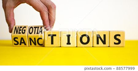 Sanctions or negotiations symbol. Businessman turns cubes, changes the word sanctions to negotiations. Beautiful yellow table, white background, copy space. Business, sanction or negotiation concept. Sanctions or negotiations symbol. Businessman turns cubes, changes the word sanctions to negotiations. Beautiful yellow table, white background, copy space. Business, sanction or negotiation concept. 88577999