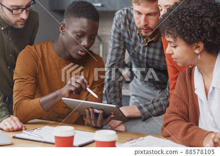 colleagues using a digital tablet during a work meeting . colleagues using a digital tablet during a work meeting . 88578105